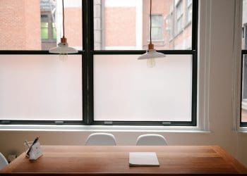 Okna należą do tych elementów domu, które wymieniamy naprawdę rzadko. Z tego względu ciężko wybrać dobre okna polegając tylko na swojej intuicji, a przecież to od nich w znaczniej mierze zależy komfort użytkowania pomieszczenia, w tym jego jasność, wyciszenie czy utrzymywanie ciepła. Przedstawiamy pięć najważniejszych parametrów, które trzeba wziąć pod uwagę, kupując okna.  1. Materiał, z którego wykonane jest okno Zanim zajmiesz się szczegółowymi parametrami, musisz ustalić jakie okno najlepiej sprawdzi się w naszym domu. Na rynku istnieją trzy najpopularniejsze materiały, z których tworzy się okna: PCV - te okna spotykane są najczęściej. Mają szeroki profil, przez co nie będą nadawać się do bardzo małych przeszkleń. Ich główną zaletą jest stosunkowa niska cena. Nie trzeba ich odnawiać co kilka lat i dobrze trzymają ciepło. Drewno - w przypadku okien drewnianych istnieje niższy poziom termoizolacji, ale węższy i sztywniejszy profil okienny. Okna drewniane sprawdzą się idealnie w przypadku małych okien. Często są wykorzystywane w przypadku zabytków i budynków stylizowanych na starsze niż są w rzeczywistości. Co kilka lat należy konserwować drewniane ramy okienne. Aluminium – jest to najrzadziej spotykany rodzaj okna. Również posiada wąską ramą okienną. Okna aluminiowe są wykorzystywane w przypadku dużych przeszkleń, bo jako jedyne dają możliwość zainstalowania ich bez dzielenia na mniejsze części, co w przypadku innych okien jest niemożliwe ze względu na wymogi producenta. Pasują doskonale do nowoczesnych wnętrz oraz biurowców. 2. Termoizolacyjność  Jedną z głównych funkcji, jakie mają pełnić okna, jest utrzymywanie ciepła w pomieszczeniu. Dlatego warto sprawdzić współczynnik przenikania ciepła w oknie. Jest kilka współczynników, a każdy informuje o przenikalności innego elementu okna. Jednak przy wyborze szczelnych okien najważniejszy jest współczynnik Uw, czyli całkowity współczynnik przenikania ciepła zarówno w szybie, jak i ramie okiennej. Im jest on niższy, tym lepiej. Na zwiększenie ciepła zostającego w domu wpływa także pakiet szyb. Najcieplejsze będą pakiety trzyszybowe, jednak ich szczelność odbywa się kosztem wpadającego do pomieszczenia światła.  Innym sposobem na zwiększenie termoizolacji w pomieszczeniu jest tzw. ciepły montaż, czyli osadzenie ram okiennych nie we wnęce okiennej, ale już w warstwie termoizolacyjnej budynku. 3. Odporność na włamania Okna antywłamaniowe są szczególnie istotne dla pomieszczeń parterowych lub na niskich pierwszych piętrach. Ich antywłamaniowe właściwości są określane współczynnikiem Rc, czyli ilością czasu, jakiego włamywacz potrzebuje, aby za pomocą siły własnego ciała, jak i używanych narzędzi wejść do środka budynku. Najniższe Rc, równe 1, to sytuacja, w której do domu można dostać się praktycznie od razu. Rc o stopniu 6, czyli najwyższym, wykazuje, że potrzeba aż 20 minut, żeby wejść do środka. Oczywiście takie okna są droższe o tych o niższych zabezpieczeniach. Należy jednak pamiętać, że wiele banków wymaga okien antywłamaniowych, aby w razie wypadku wypłacić pieniądze z polisy mieszkaniowej.  Przy sprawdzaniu tego współczynnika w sklepie poproś sprzedawcę o wskazanie konkretnych, zgodnych z polskim prawem certyfikatów, ponieważ często antywłamaniowe okna to tylko marketingowy chwyt bez pokrycia w rzeczywistości. 4. Dźwiękoszczelność W przypadku domów znajdujących się blisko hałaśliwych ulic czy torów tramwajowych, równie istotna będzie dźwiękoszczelność. Poziom dźwiękoszczelności obrazuje wskaźnik Rw (współczynnik izolacji akustycznej właściwej) podawany w decybelach. Im jest on wyższy, tym okna wpuszczają mniej dźwięków do wewnątrz. Najwyższą izolacją akustyczną mogą poszczycić się okna z szybami warstwowymi klejonymi, które potrafią wyciszyć dźwięki aż o 50 dB. W domach o przeciętnym natężeniu hałasu dochodzącego z zewnątrz zwykle instaluje się okna o Rw pomiędzy 30 a 35 dB. 5. Współczynnik transmisji światła Od współczynnika transmisji światła zależy jasność pomieszczeń. Jest ona szczególnie przydatna w przypadku pomieszczeń o małych oknach i tych, do których naturalne światło dociera przez niewiele godzin w ciągu dnia. Lt, czyli współczynnik przepuszczalności światła, jest wyrażany w procentach lub ułamkach dziesiętnych. Im wyższy, tym więcej światła wpadnie do domu (zamiast zostać pochłonięte lub odbite). Dzięki wysokiemu Lt okna wydają się znacznie większe, niż są w rzeczywistości. Zwykle, im grubsze okna, tym mniejszy współczynnik transmisji światła, dlatego warto rozsądnie wybrać, co jest dla nas ważniejsze - termoizolacja, czy przepuszczalność światła.